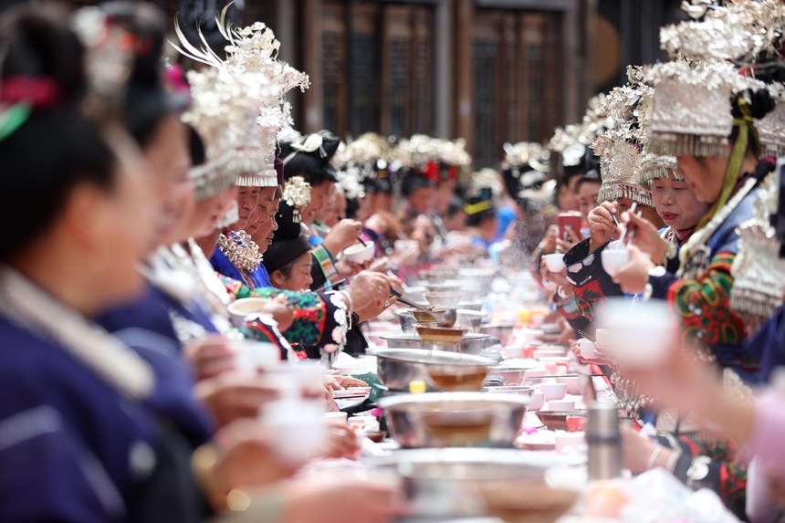 10月31日，在丹寨縣萬達(dá)小鎮(zhèn)，身著節(jié)日盛裝的苗族同胞在長桌宴上品嘗美食。