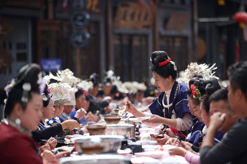 10月31日，在丹寨縣萬達(dá)小鎮(zhèn)，身著節(jié)日盛裝的苗族同胞在長桌宴上品嘗美食。