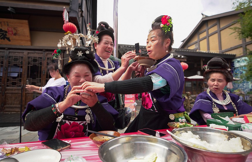 10月31日，在丹寨縣萬達小鎮(zhèn)，身著節(jié)日盛裝的苗族同胞在長桌宴上相互敬酒菜。