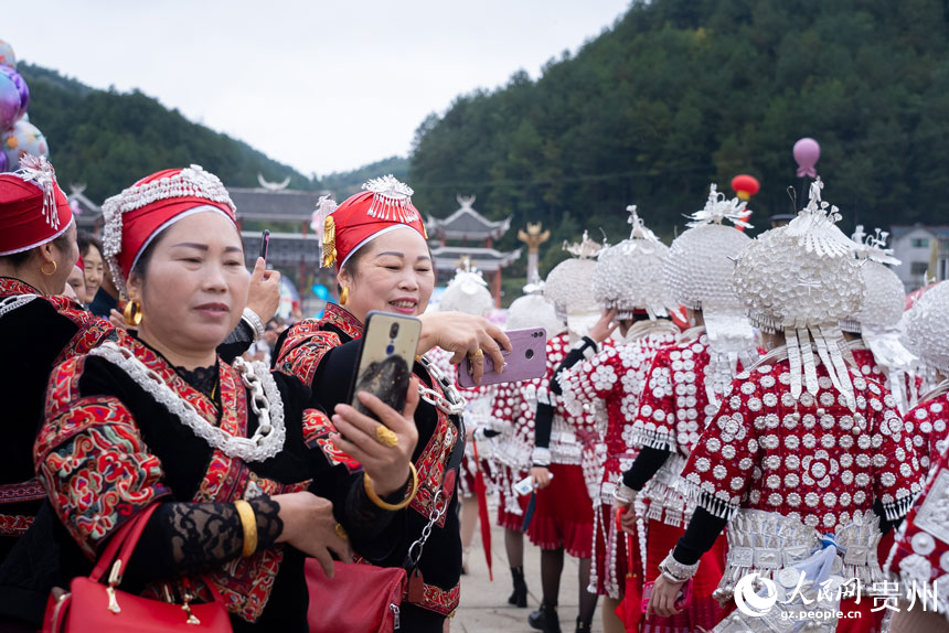 身著盛裝參加“蘆笙會”的苗族同胞為參加游演的同伴拍照。人民網(wǎng)記者 涂敏攝