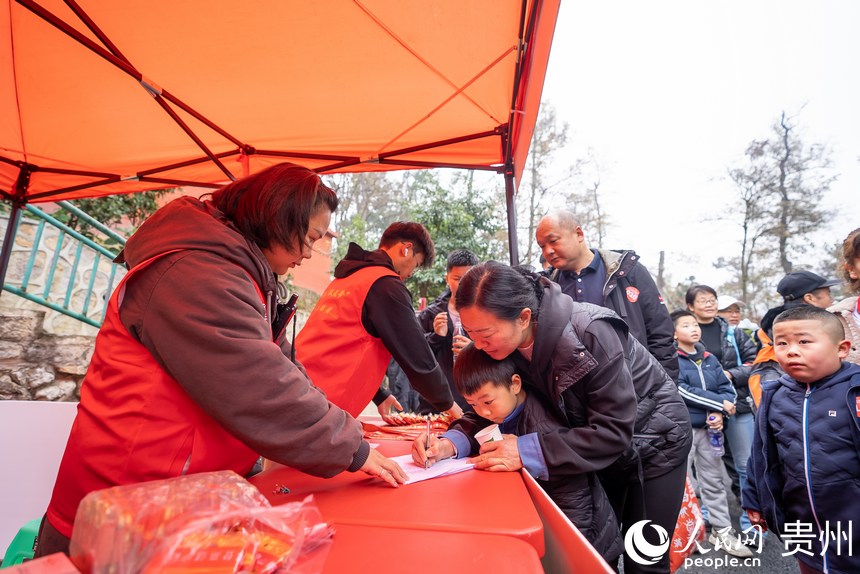 參與貴陽貴安第53屆全民健身登高迎新跑的市民在終點(diǎn)登記領(lǐng)取紀(jì)念獎牌。人民網(wǎng)記者 涂敏攝