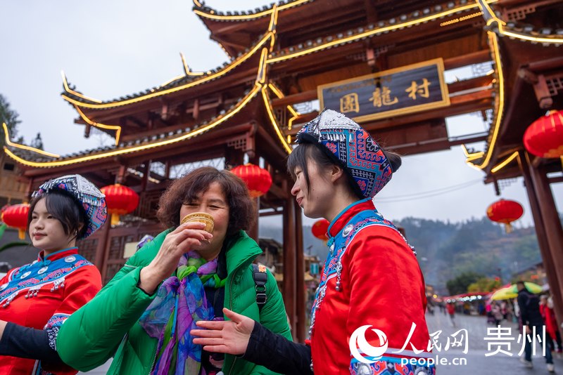 團(tuán)龍村“幸福土家過趕年”活動(dòng)現(xiàn)場，游客品嘗攔門酒。人民網(wǎng)記者 涂敏攝