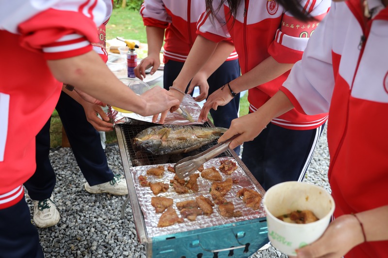 學(xué)生們相互配合烤魚(yú)、烤肉。