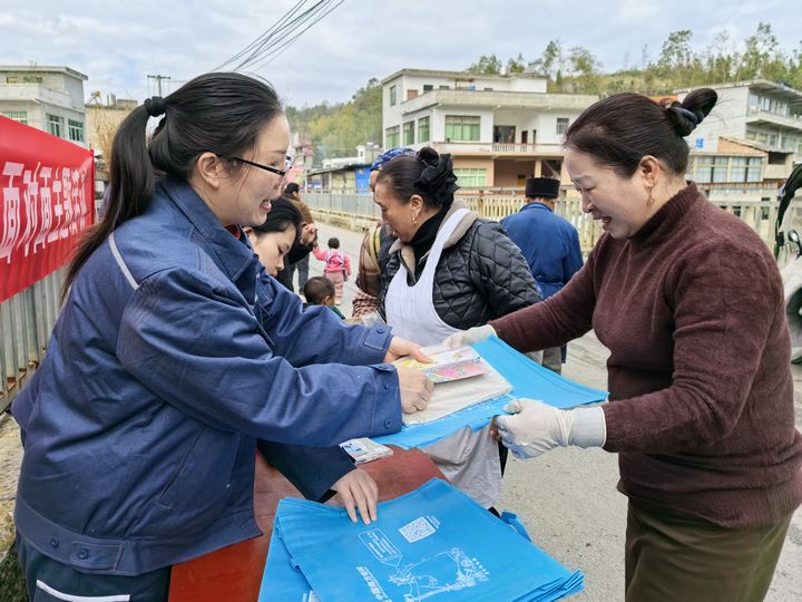 工作人員正在向趕集的村民發(fā)放安全用電宣傳冊。.jpg