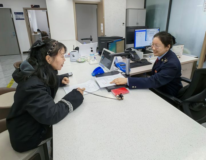 都勻市稅務(wù)局干部為居民講解契稅新政策。